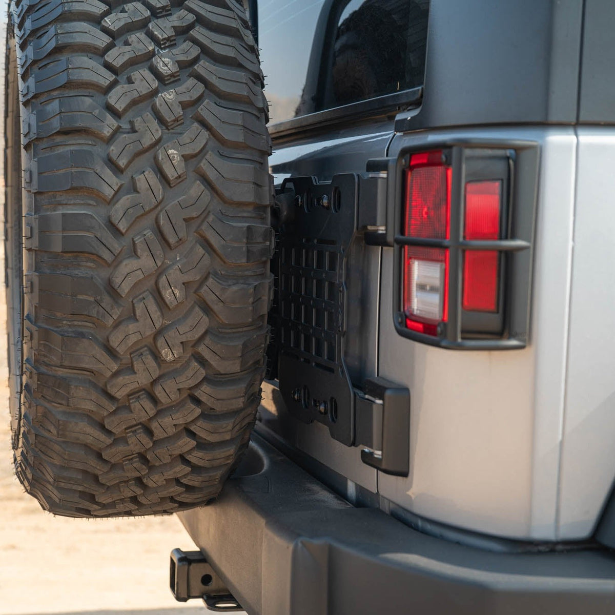 Close-up of a Jeep Wrangler JK Tailgate Reinforcement Molle Panel and tail light with a natural outdoor background