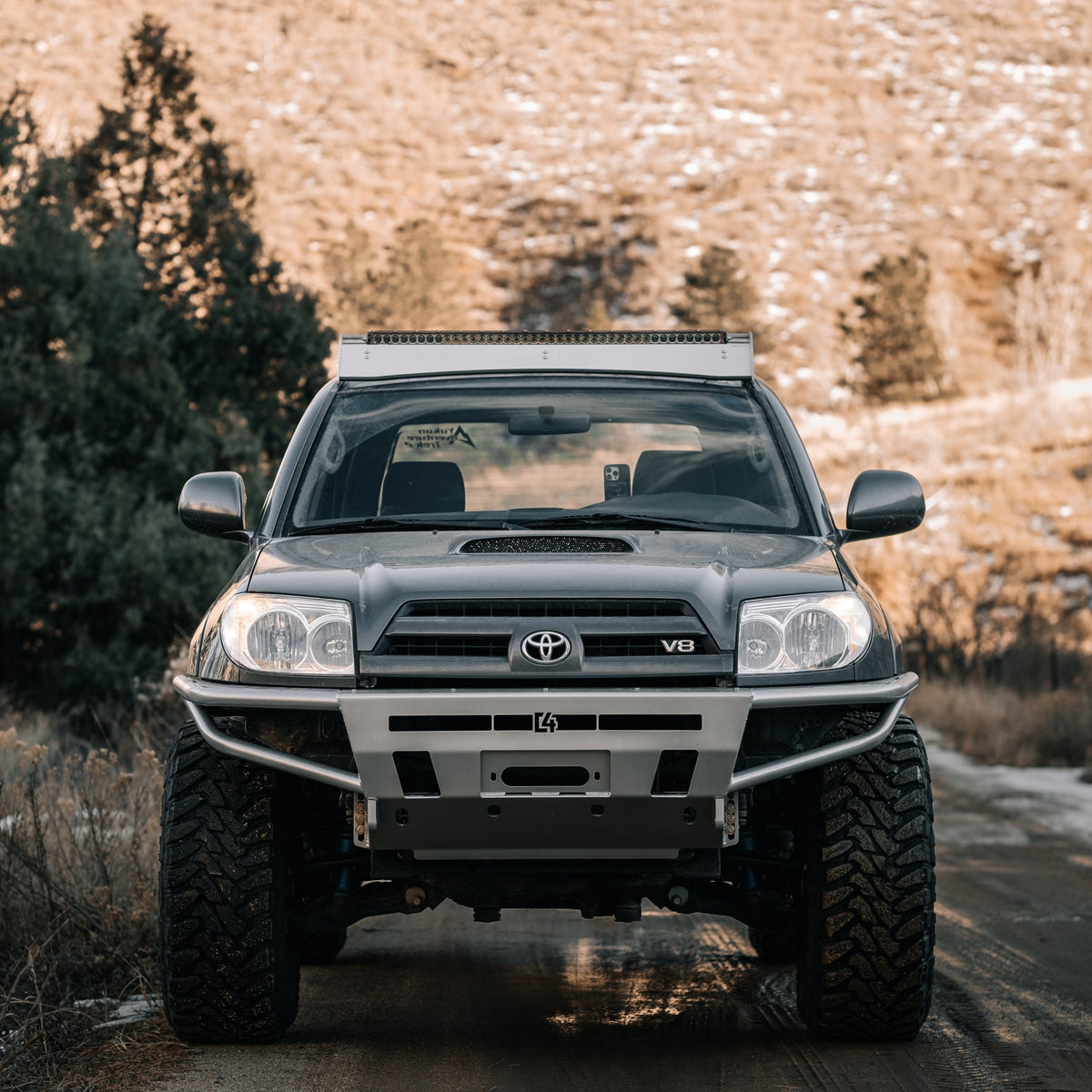 Front-on view of a grey Toyota 4Runner on a mountain road with a silver Hybrid bumper from C4 mounted on the front.