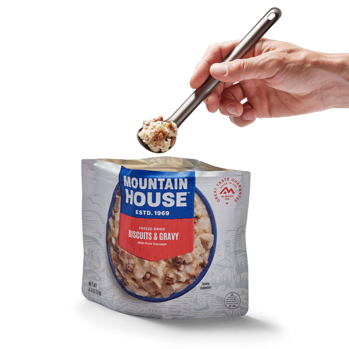 Person scooping out spoonful of Mountain House Biscuits & Gravy from pouch.