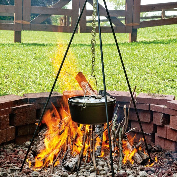 Tripod being used to hold dutch oven over fire in firepit.