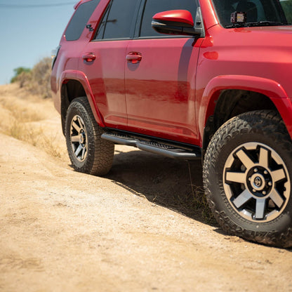 Red SUV driving on a dirt road with a clear sky