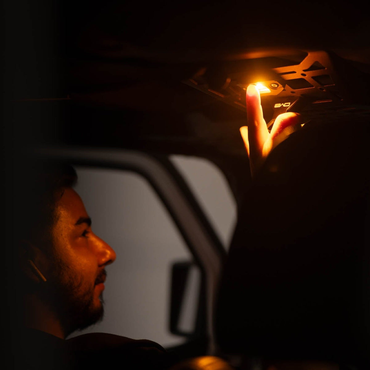 Man pushing on/off button of the Elite White/Amber Push Button Dome Light by DV8 Offroad