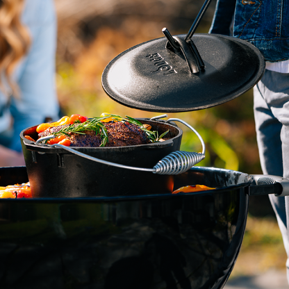 Beef chuck roast being prepared in dutch oven on grill.