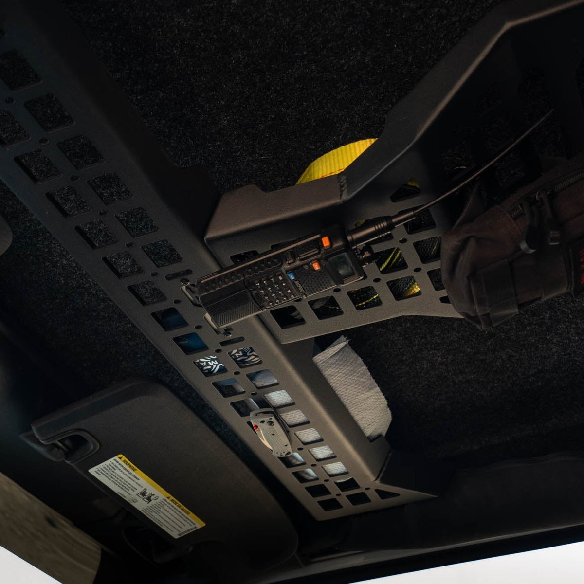 Overhead Molle Storage Panel for 2007-2018 Jeep Wrangler JK with CB radio and knife holder installed, and items stored above the panel