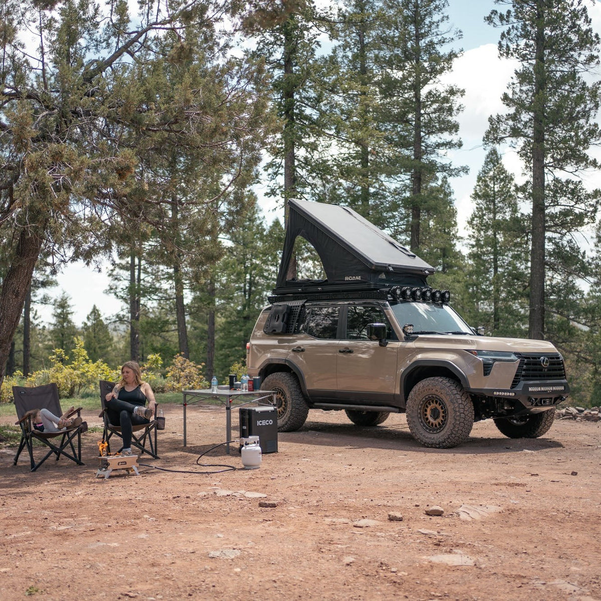 Camp setup with the GX 550 fully equipped. The SUV is equipped with off road bumpers, roof rack, tent, light brackets, and molle panels from Rago Fabrication.