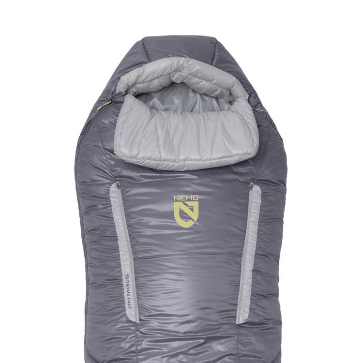 The Forte™ Endless Promise® Women’s Synthetic Sleeping Bag by NEMO Equipment is a gray, mummy-style 3-season bag with a hood and dual vertical zippers, designed for comfort in various conditions and featuring the NEMO logo on the front.