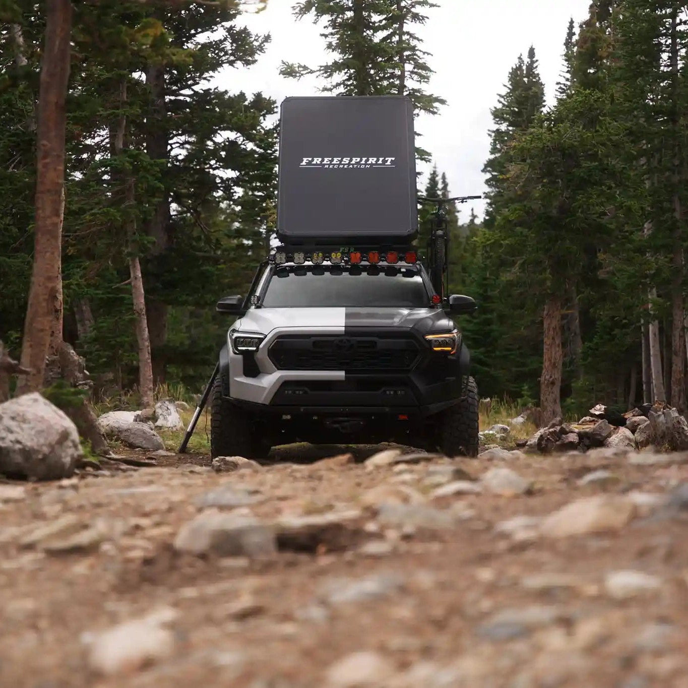 Black & white Toyota Tundra parked in a wooded campsite with an FSR Aspen Pro Standard rooftop tent setup while truck camping