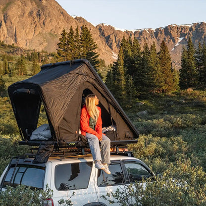 Person sitting inside an open Free Spirit Recreation Aspen Pro rooftop tent installed on a 3rd Gen 4Runner with mountains and trees in the background