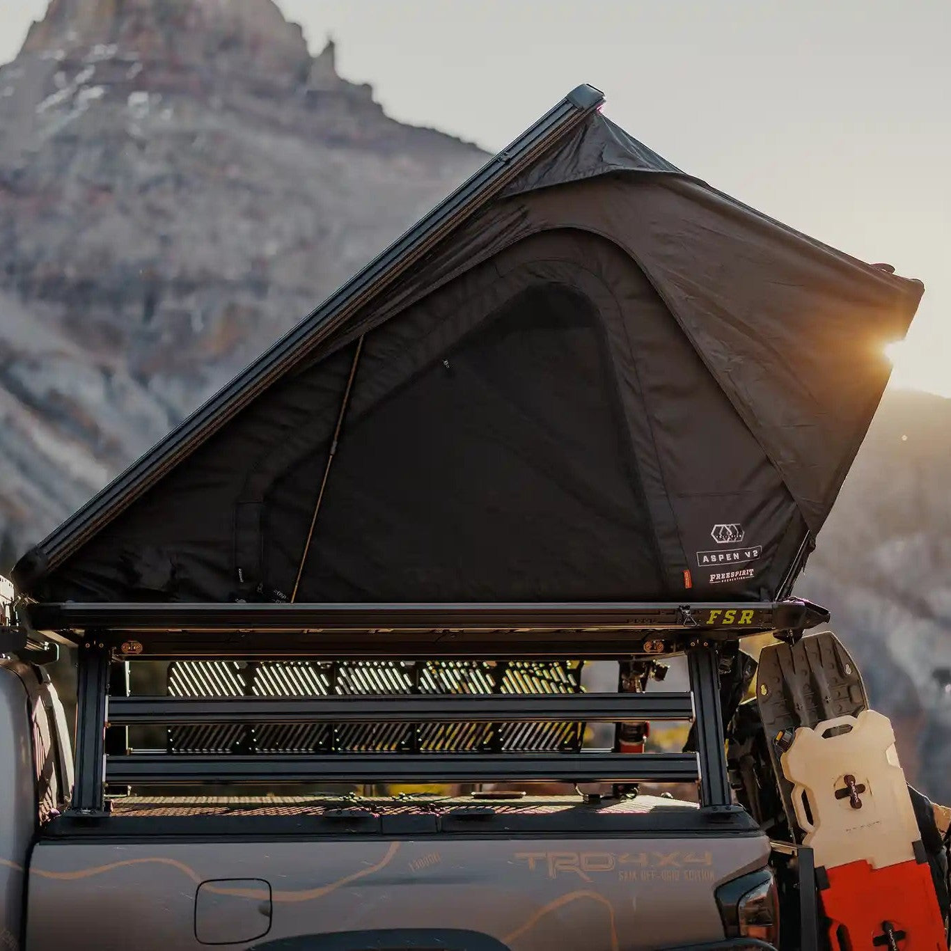 FSR Aspen Pro XL rooftop tent set up on a truck bed rack against a mountainous landscape at sunset.