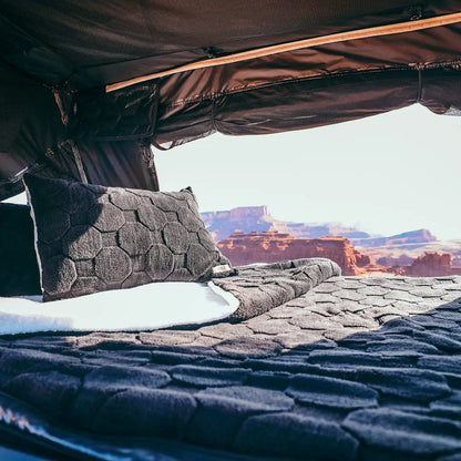 Interior of an FSR Rooftop Tent with Cloud Comforter and pillow cases setup with a scenic desert landscape visible behind the bedding set