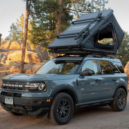 Ford Bronco with a Pair of FSR Crossbars installed on a Free Spirit Recreation hard shell roof top tent with a bike mount installed for carrying a mountain bike on top of the RTT while camping