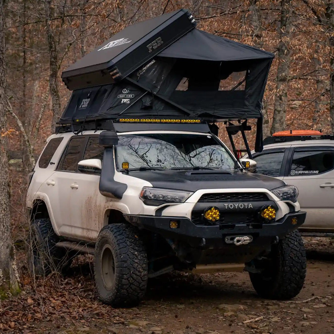 Toyota 4Runner with a Kali King rooftop tent installed on the roof rack and open in a forested campsite