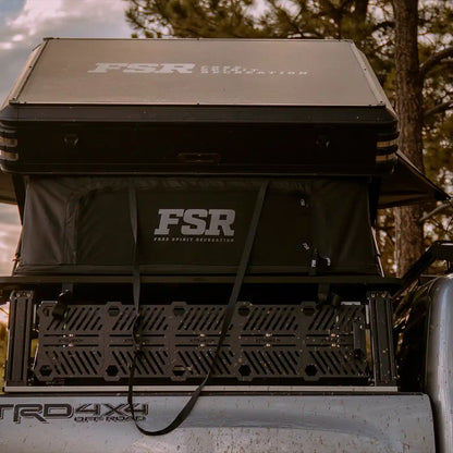 Rear-facing image of the FSR rooftop tent installed on a truck bed rack with a scenic wooded  sunset view in the background