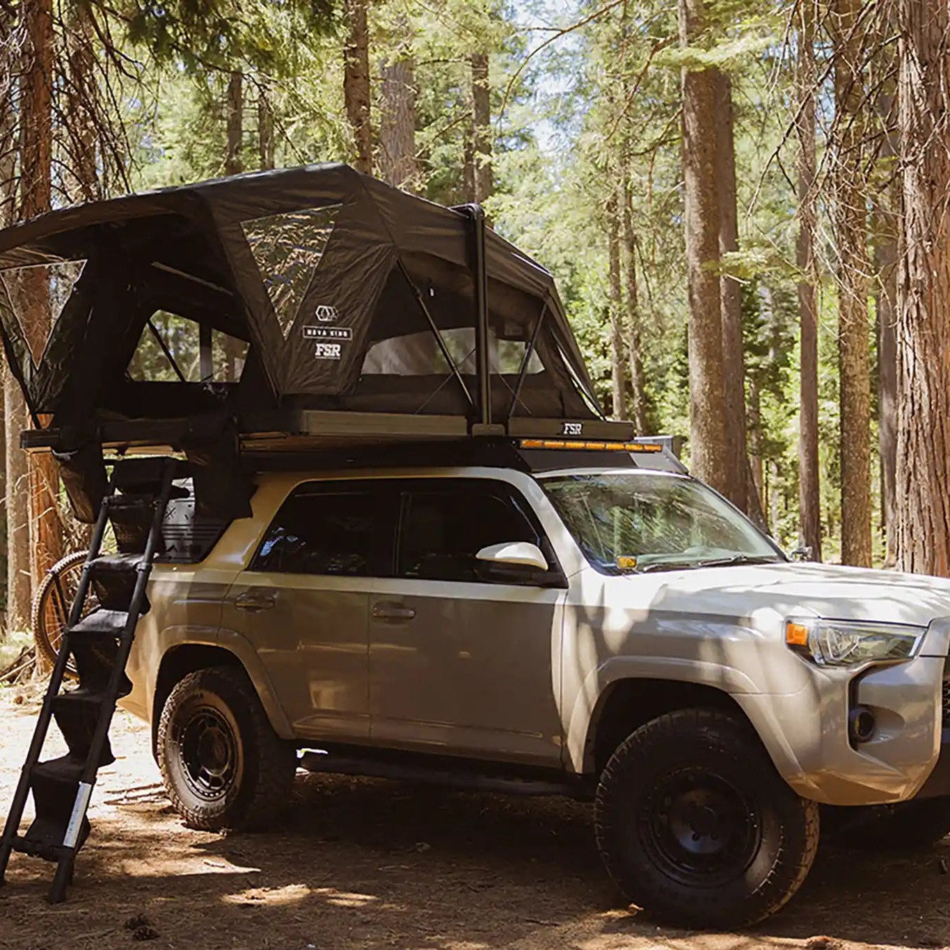 Silver Toyota 4Runner with roof rack in a forest with FSR Nova King Rooftop tent deployed.