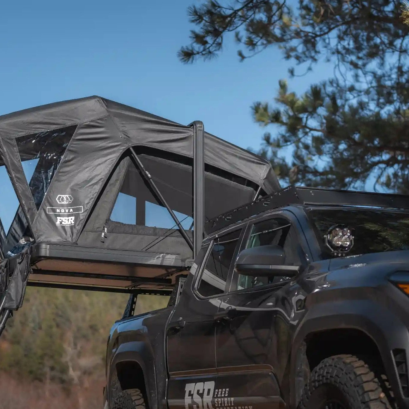Free Spirit Recreation Nova Standard rooftop tent installed on a Tacoma bed rack and setup in a wooded campsite