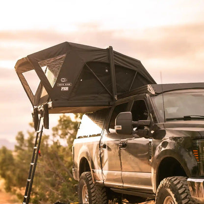 Black truck with a Nova King rooftop tent setup camping in a natural setting at dusk