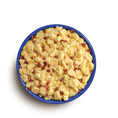 Aerial view of a blue camping bowl filled with scrambled eggs and bacon bits
