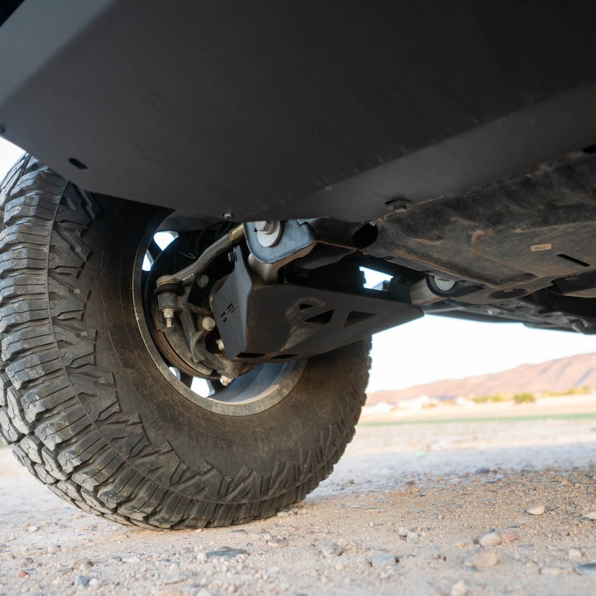 Close-up of bronco with the A-Arm skid plate on a gravel surface.